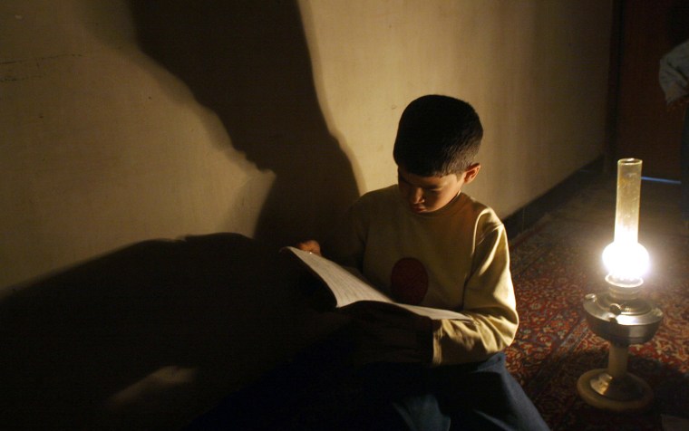 An Iraqi boy studies under an oil lamp, in Baghdad, March 2, 2006 during an electricity outage.