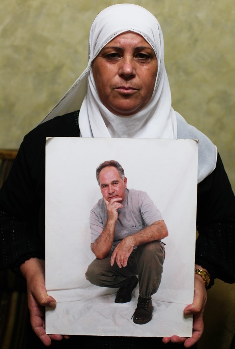 epa03820509 Samia Nasser (L), the wife of Muhammad Ibrahim Nasser who has been jailed in the Israeli Ramon prison since 1985, holds her husbands image as she waits for the announcement of the final list of prisoners who will be released as a goodwill gesture from Israel in return for peace negotiations, at her home in the West Bank village of Safa near Ramallah, 11 August 2013. EPA/ATEF SAFADI