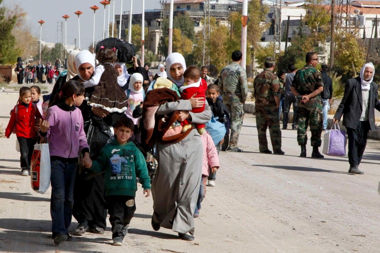 Syrian families leave the besieged town of Mouadamiya, which is controlled by opposition fighters, on Tuesday.