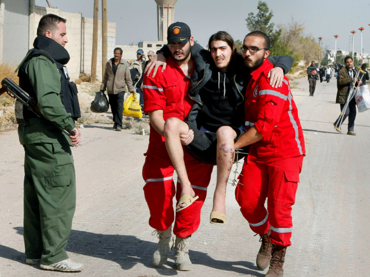 Volunteers from the Syrian Arab Red Crescent carry a sick man as Syrian families leave the besieged town of Mouadamiya.