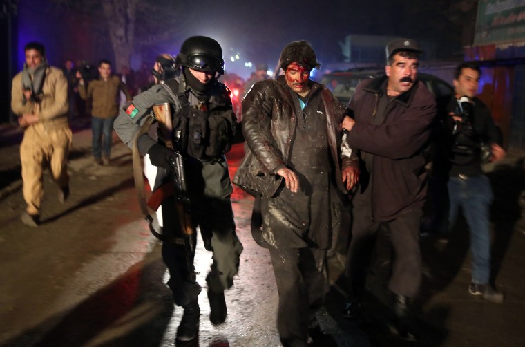 Afghan police forces assist an injured man at the site of an explosion in Kabul, Afghanistan, on Friday.