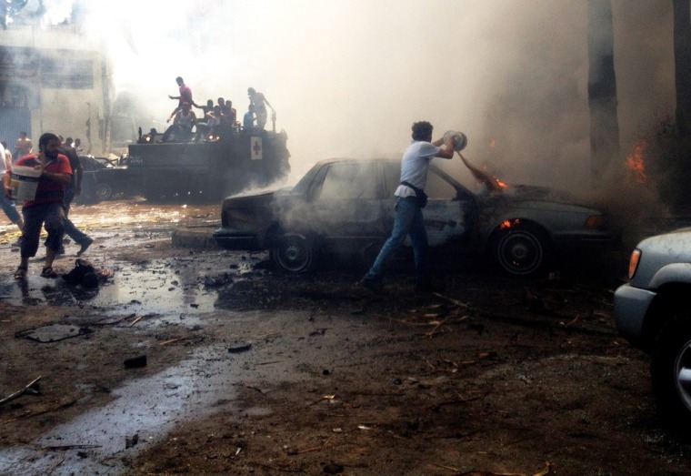 Men try to extinguish fires at the site of an explosion in the northern city of Tripoli, Lebanon.