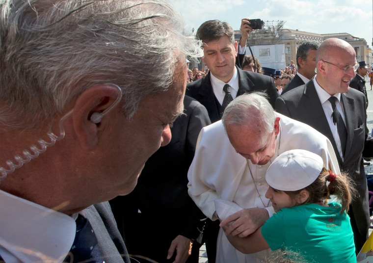 Pope Francis is hugged by a young girl after stepping out of his popemobile to walk the last part of his way to the altar, to deliver his weekly general audience in St. Peter's Square at the Vatican, Wednesday, May, 8, 2013.