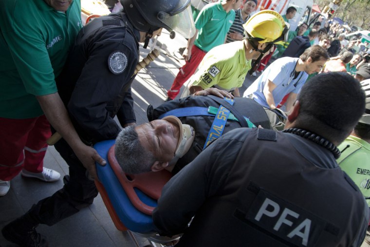 Police and paramedics carry a wounded passenger to an ambulance after a commuter train slammed into the end of the line when arriving to Once Central station in Buenos Aires, Argentina, early on Saturday.