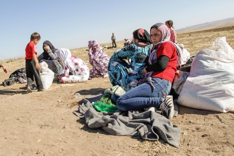 Syrians wait near the border crossing between Syria and Iraq in Semalka, Syria, on Oct. 21.