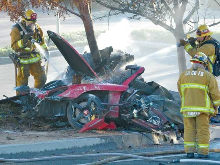 Firefighters hose down the remains of a red 2005 Porsche Carrera GT following a crash in Valencia, Calif., which killed actor Paul Walker and a friend.