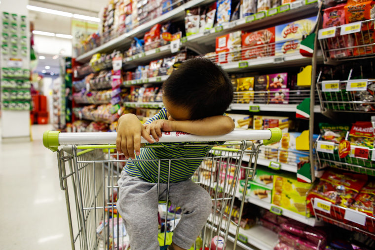 A boy sleeps in a shopping cart at a department store in Bangkok October 29, 2013. The Thai economy has struggled free of recession, but latest data i...