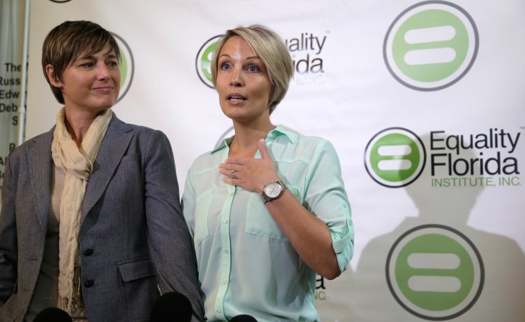 Melanie Alenier, right, speaks as her partner Vanessa Alenier looks on during a news conference, Tuesday, Jan. 21, 2014 in Miami Beach, Fla. Six gay couples including the Aleniers, filed a lawsuit Tuesday seeking to overturn Florida's ban on same-sex marriage.