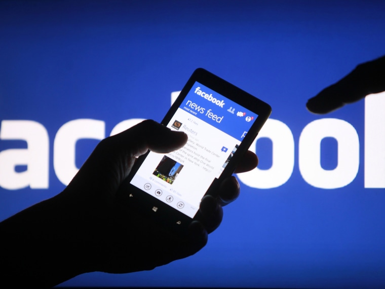 A smartphone user shows the Facebook application on his phone in the central Bosnian town of Zenica, in this file photo illustration from May 2, 2013....