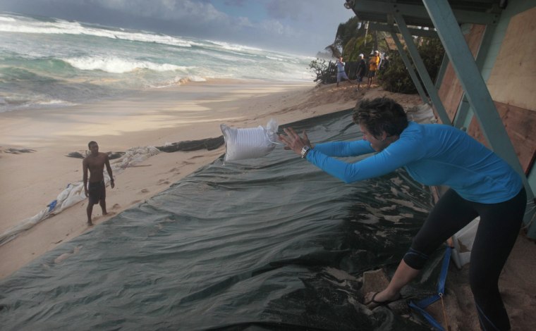 Alice Lunt, right, tosses a sandbag to a volunteer as high surf hits the North Shore of the island of Oahu, near Sunset Beach, Hawaii, on Jan. 22, 2014.