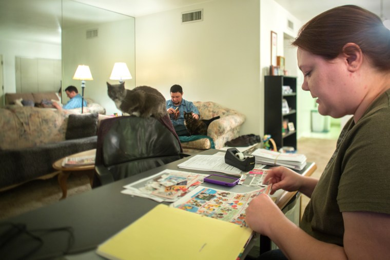 Erika Trowell organizes her coupon collection at home in Phoenix, Ariz., while her husband, Ben, reads a book. Trowell estimates that she saves between $30 and $50 per month by using coupons.