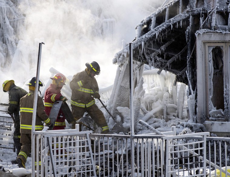 Rescue personnel search through the icy rubble Friday of a fire that destroyed a senior residence in Quebec.