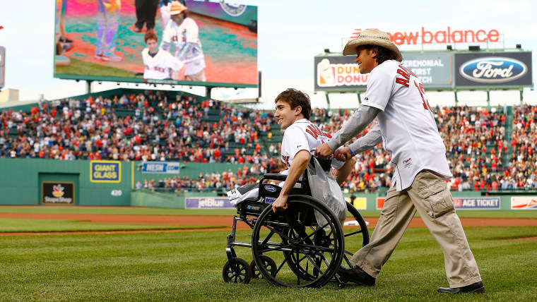 BOSTON, MA - MAY 28: Boston Marathon bombing victim, Jeff Bauman, is wheeled out to the pitchers mound before throwing out the ceremonial first pitch ...