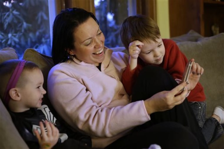 Julie Young, a Boston-based behavioral analyst, center, sits with her sons Nolan, 3, left, and Jameson, 4, right, while looking at a smart phone at th...