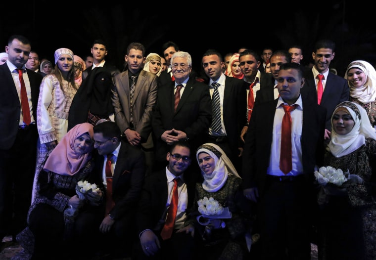 Couples pose for pictures with Palestinian President Mahmoud Abbas, center, during a mass wedding ceremony in the West Bank city of Jericho on Jan. 28, 2014.