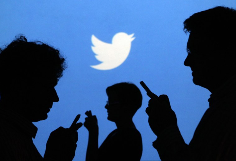 People holding mobile phones are silhouetted against a backdrop on which the Twitter logo is projected, in this file picture illustration taken in War...