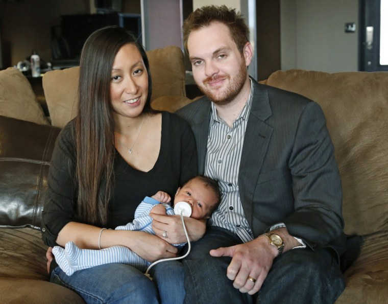 Jennifer Rogers, left, and her husband Nyle Rogers, right, smile as they hold their baby Jack Nicolas Rogers, in their home in Edmond, Okla., Tuesday, Jan. 14, 2014.