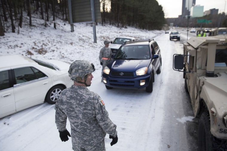 Georgia National Guardsman Command Sgt. Maj. Buddy Grisham (C) is joined by fellow troops as they help people get their stranded cars out of the snow in Atlanta, Georgia January 29, 2014. A rare ice storm turned Atlanta into a slippery mess on Wednesday, stranding thousands for hours on frozen roadways and raising questions about how city leaders prepared for and handled the cold snap that slammed the U.S. South.