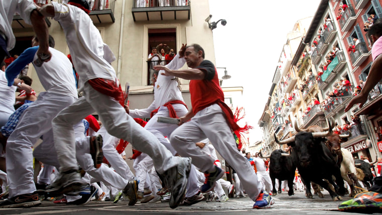 PAMPLONA, SPAIN - JULY 10:  Revellers run with Garcigrande's fighting bulls along the Curva de Estafeta during the fifth day of the San Fermin Running...