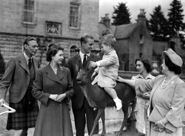 Britain's Prince Charles, watched by, from left, King George VI, Princess Elizabeth, Prince Philip, Princess Margaret and Queen Elizabeth, sits on a s...