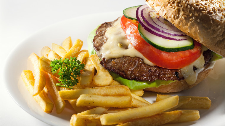 Hamburger with vegetables on plate.