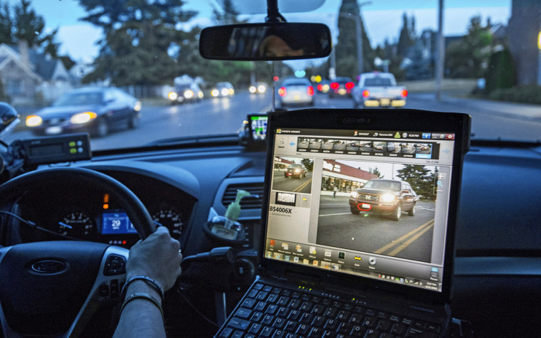 Tacoma Police Officer Matthew Graham monitors an automatic license plate reader as he cruises during a graveyard shift, June 21, 2014.  In this photo the computer's screen shows the car seen at left with the license plate circled in red. The whole screen would have turned red if the license plate matched one from the \"hot sheet\", indicating a possible stolen car.