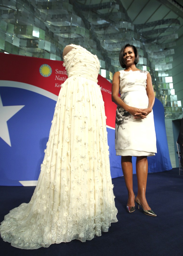 First lady Michelle Obama stands with the gown that she wore to the 2009 inaugural ball as she donates it to the Smithsonian's National Museum of Amer...