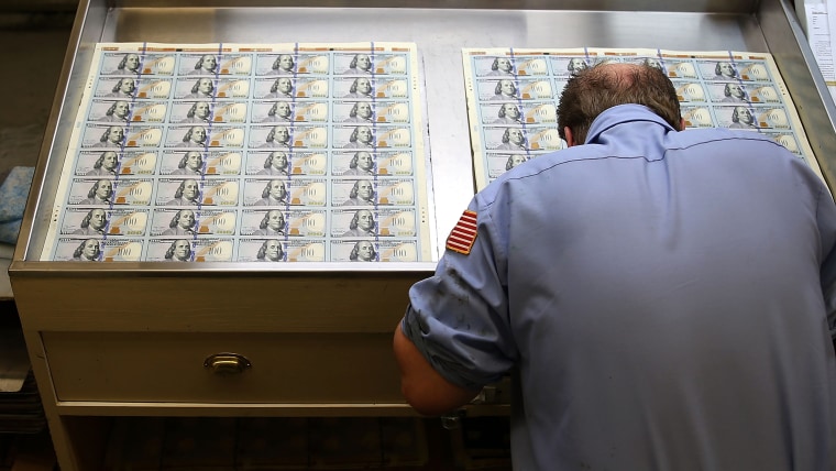 A worker inspects newly redesigned $100 notes during the printing process at the Bureau of Engraving and Printing last year.