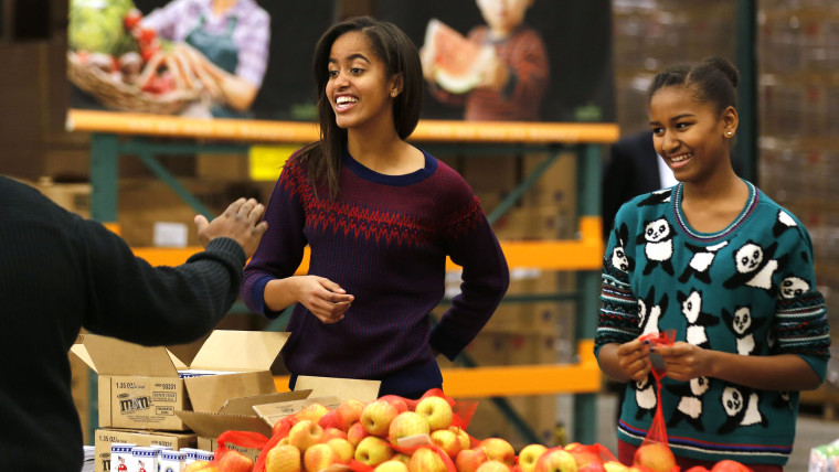 Malia (L) and Sasha (R), daughters of U.S. President Barack Obama and first lady Michelle Obama hand out Thanksgiving food at the Capital Area Food Ba...