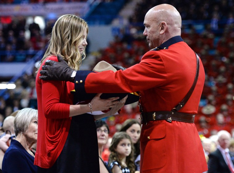 Royal Canadian Mounted Police Commissioner Bob Paulson, right, presents Constable Dave Ross's widow Rachael with the slain RCMP officer's Stetson duri...