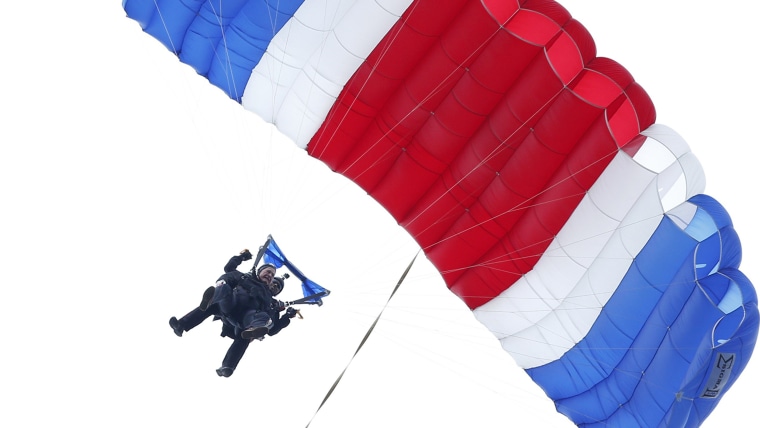 Former President George H.W. Bush, strapped to Sgt. 1st Class Mike Elliott, a retired member of the Army's Golden Knights parachute team, floats to the ground during a tandem parachute jump near Bush's summer home in Kennebunkport, Maine, on Thursday in celebration of his 90th birthday.