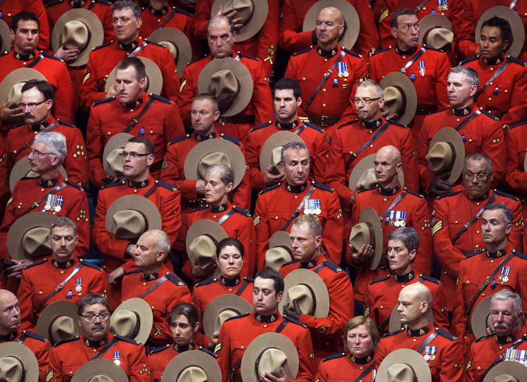 RCMP officers stand in silence during the regimental funeral of three slain officers at the Moncton Coliseum on Tuesday, June 10, 2014, in Moncton, Ne...