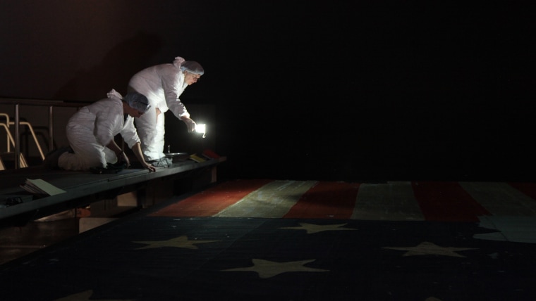 Jennifer Jones and textile conservator Suzanne Thomassen-Krauss inspect the anthem-inspiring flag during preservation.