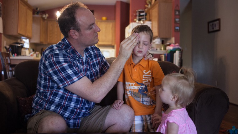 Corey Fontenot's daughter, Cora, 16 months, looks on as her father applies sunscreen to son Isaac's face.