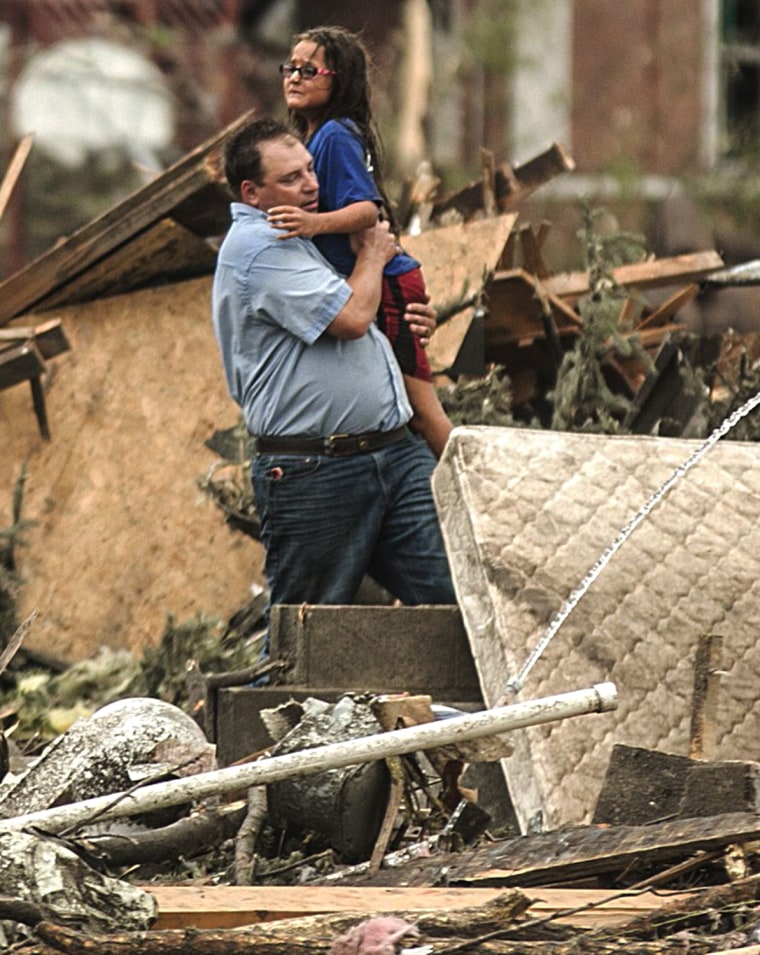 A man holds a girl after she was pulled from the basement of her destroyed home in Pilger, Neb., Monday, June 16, 2014. A hospital spokeswoman says at...