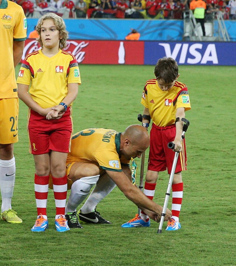 Mark Bresciano, a midfielder for Australia, bends down to help tie the shoe laces of a boy on crutches ahead of a World Cup match against Chile in a touching photo that has warmed hearts across the world.