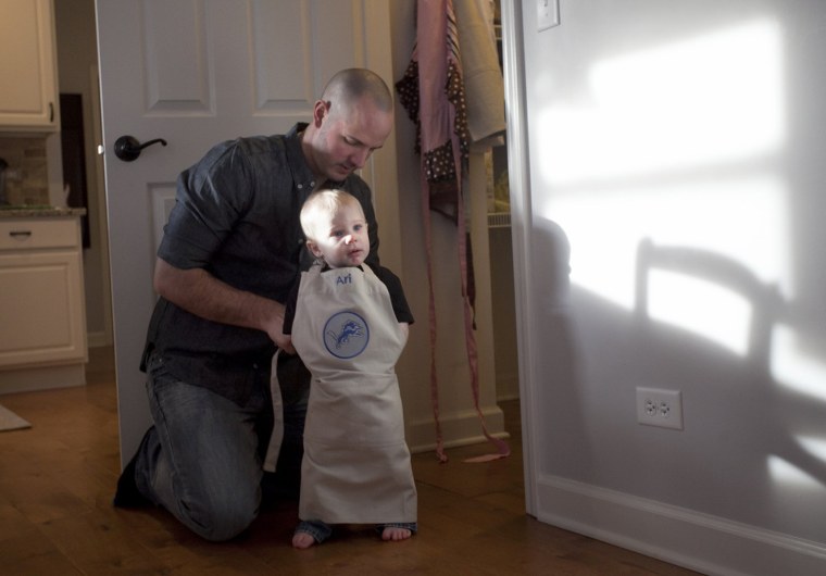 Juip puts an apron on his son Ari while making dinner at their home.