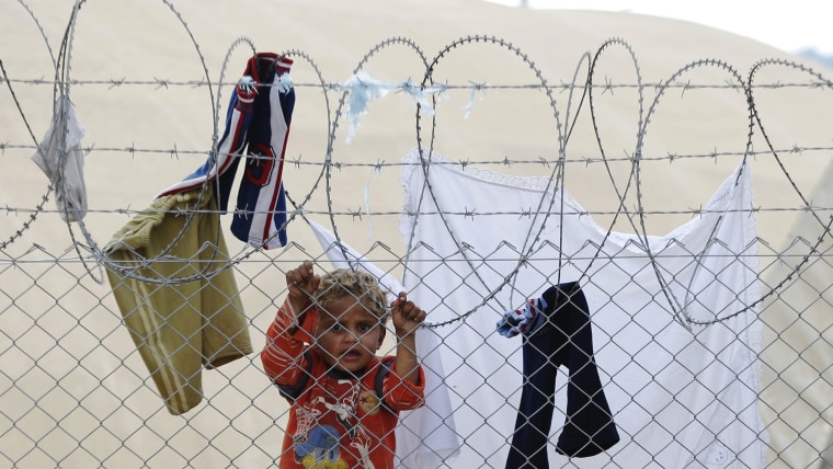 A newly arrived Syrian refugee child is seen behind the fences at Ceylanpinar refugee camp near the border town of Ceylanpinar, Sanliurfa province, No...