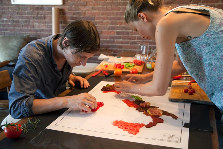 Hargreaves and Levin painstakingly arrange tomatoes around a stencil of Italy.