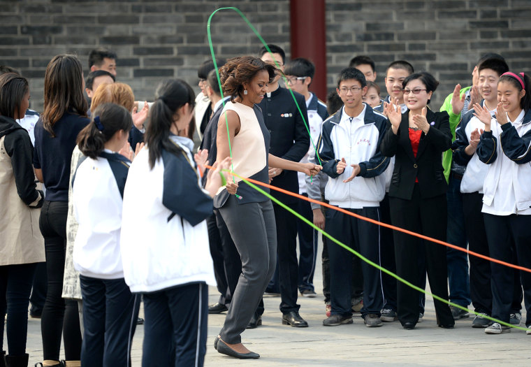 US First Lady Michelle Obama (C) skips in front of Chinese school children on the City Wall in Xian in China's central Shaanxi  province on March 24, ...