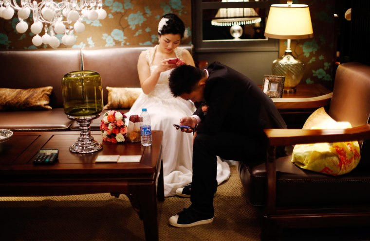 A couple waits to participate in a staged mass wedding, organised as part of a matchmaking event to inspire singles to get married, in a suburban area...