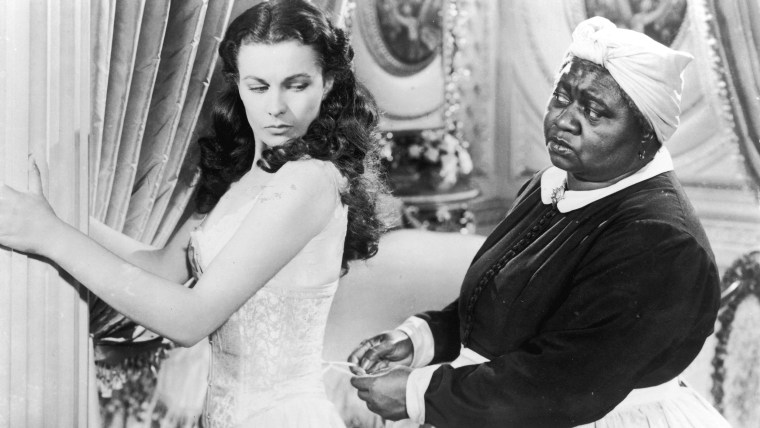 British actor Vivien Leigh (1913-1967) holds on to a pillar as American actor Hattie McDaniel (1895-1952) tightens her corset in a still from the 1939 film \"Gone with the Wind.\"