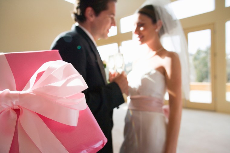 Bride and groom holding hands at wedding, smiling, focus on wedding gift in foreground, msnbc stock photography. 