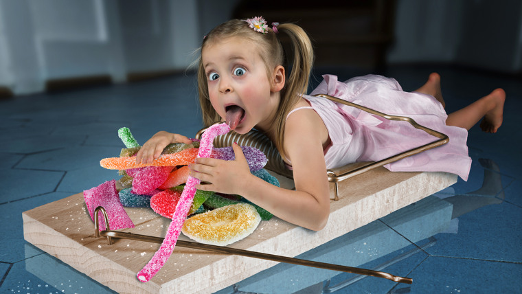 Image: Small girl caught in a giant mousetrap eating candy