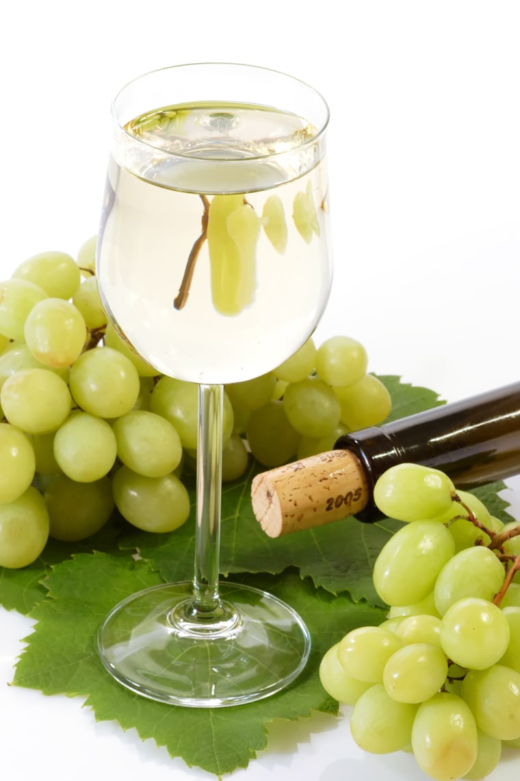 Glass of wine with grapes, leaves and bottle on white background