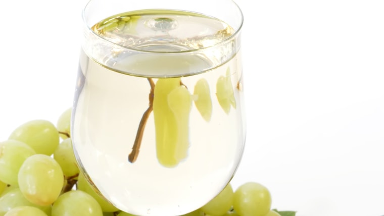 Glass of wine with grapes, leaves and bottle on white background