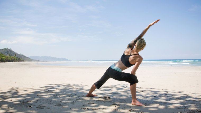 Young woman practicing yoga on the beach