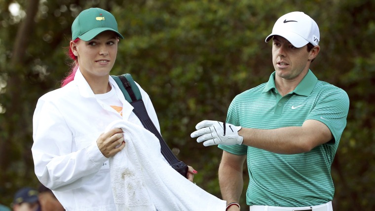 Tennis player Caroline Wozniacki of Denmark (L) works as the caddie for her boyfriend, Northern Ireland's Rory McIlroy, during the Par 3 Contest ahead...