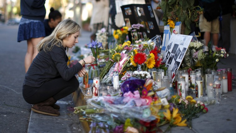 A woman lights a candle at a makeshift shrine for 20-year-old UCSB student Christopher Michael-Martinez outside a deli that was one of nine crime scen...