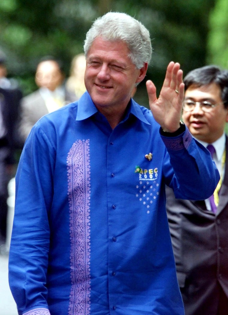 Dressed in a royal blue shirt, President Clinton waves to photographers as he walks to the APEC leaders' lunch at the Jerudong Polo Club in Bandar Ser...